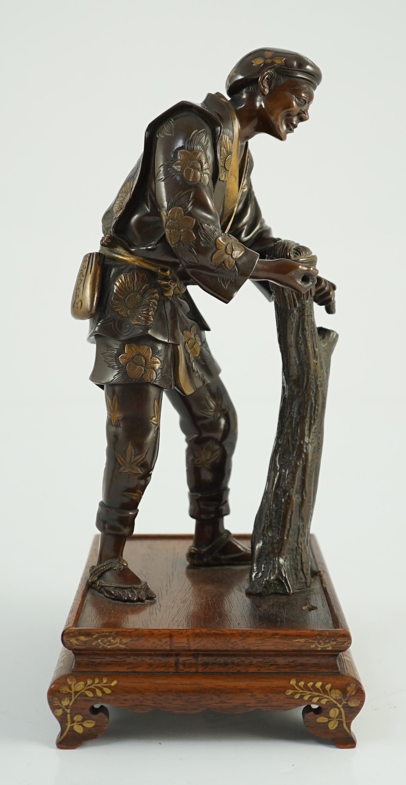 A Japanese brown patinated and gilded bronze figure of a woodworker, in Miyao style, Meiji period, 27.5cm high